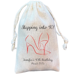 Peut inclure: Un sac en tissu blanc avec cordon de serrage, sur lequel est inscrit le texte "Stepping into 40!" et un contour rouge d'un talon haut. Le sac porte &eacute;galement le texte "Jennifer's 40th Birthday March 2025".