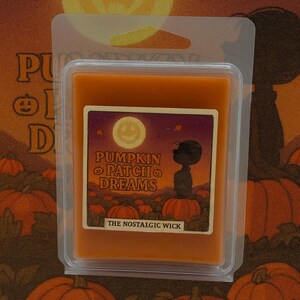 May include: An orange wax melt in a clear plastic container. The label reads "Pumpkin Patch Dreams" with a cartoon illustration of a character standing on pumpkins under a full moon. The text "The Nostalgic Wick" is also present.