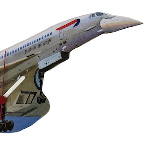 May include: A wall clock in the shape of a Concorde jet, featuring the British Airways livery. The clock face is a detailed illustration of the aircraft, with white clock hands and the British Airways logo. The clock is made of wood.