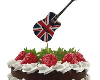 May include: A chocolate cake decorated with white frosting and red strawberries. A guitar with a Union Jack design is stuck into the cake.