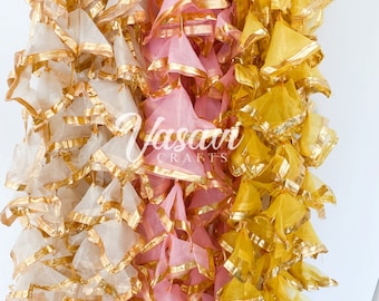 May include: Three strands of decorative fabric garland with gold trim. The garland is made of layers of sheer fabric in white, pink, and yellow.