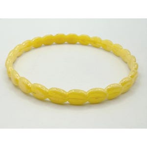 May include: A bright yellow bangle bracelet featuring a continuous series of small, rounded, oval-shaped links connected to form a circular band. The surface of the bracelet has a smooth, glossy finish with a consistent, vibrant yellow color throughout.