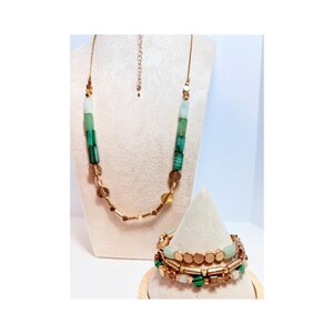 May include: A necklace and a multi-strand bracelet set featuring a combination of metallic gold-toned cylindrical and disc beads interspersed with smooth light green and dark green striped rectangular beads, creating a coordinated jewelry ensemble.