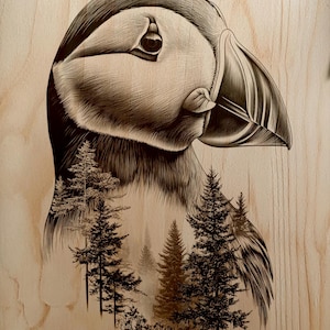 May include: A detailed wood-burned artwork featuring a puffin bird with a forest scene incorporated into its form. The artwork is rendered in shades of brown and black, with intricate line work. The background is a light wood grain.