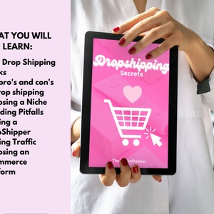 Może przedstawiać: R&oacute;żowy tablet z ikoną białego koszyka na zakupy i tekstem "Dropshipping Secrets" na ekranie. Tablet jest trzymany przez dłonie osoby.