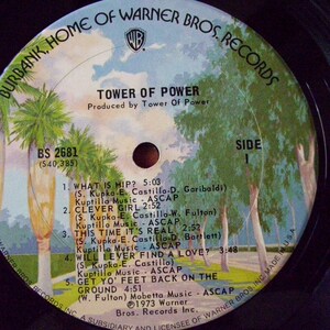 Pu&ograve; includere: Un disco in vinile vintage di Tower of Power, intitolato "What Is Hip?" Il disco &egrave; su Warner Bros. Records e presenta un paesaggio blu e verde con palme sulla copertina.
