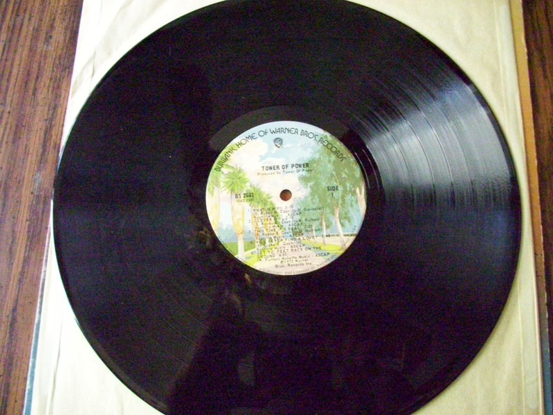 Pu&ograve; includere: Disco in vinile nero con un'etichetta bianca che dice "Tower of Power" e "Warner Bros. Records".