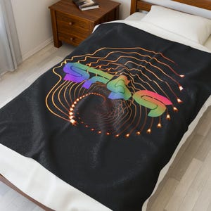 May include: Black blanket with a colorful graphic design. The design features a rainbow-colored shape with the word "SOUL" and orange lines radiating outward. The blanket is on a bed with a white pillow.