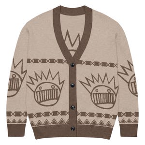 May include: Beige cardigan sweater with brown trim and buttons. The sweater features a repeating brown graphic pattern of crowns and faces. The V-neck cardigan is a button-up style.