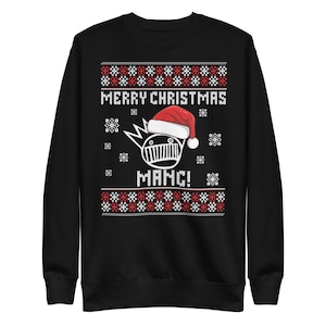 May include: Black sweatshirt with a festive design. The text "MERRY CHRISTMAS" is displayed above a graphic of a character wearing a Santa hat. The word "MAMC!" is below the graphic. Red and white snowflake and geometric patterns are featured.