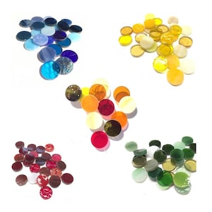May include: A collection of colorful, round glass mosaic tiles in various shades of blue, yellow, orange, red, and green. The tiles are scattered on a white surface, showcasing their glossy finish and diverse hues, perfect for craft projects.
