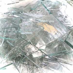 May include: A pile of clear glass shards, some with a frosted texture.