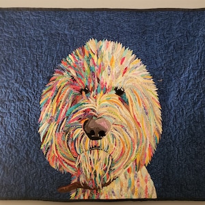 Pode incluir: Um cobertor abstrato e colorido que representa o rosto de um c&atilde;o. A pelagem do c&atilde;o &eacute; feita de v&aacute;rios tons de azul, verde, amarelo, laranja e vermelho. O nariz do c&atilde;o &eacute; marrom e seus olhos s&atilde;o pretos. O fundo do cobertor &eacute; azul escuro.