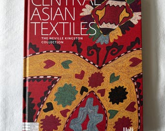 May include: A hardcover book titled Central Asian Textiles: The Neville Kingston Collection. The red cover features a large, intricate, embroidered pattern in yellow, green, and blue. The Hali logo is printed in the bottom right corner.