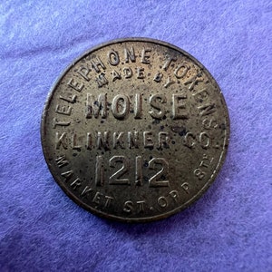 May include: A brass telephone token with the text "Telephone Token Made By Moise Klinkner Co. Market St. Opp. Sta. 1212"