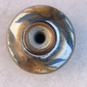 May include: A ceramic vase with a brown, blue, and white glaze. The vase has a wide base and a narrow neck.