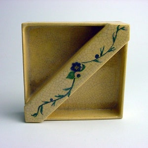 May include: A square ceramic dish with a crackled glaze and a floral design in shades of green and blue. The dish has a divided section, creating a unique shape.