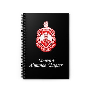 May include: A black spiral-bound notebook featuring a red and white emblem with Greek letters and the words "Concord Alumnae Chapter." The notebook has a clean, minimalist design.