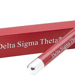 May include: A red pen with a silver cap and a white inscription that reads "Delta Sigma Theta®". The pen is in a red box with the same inscription.