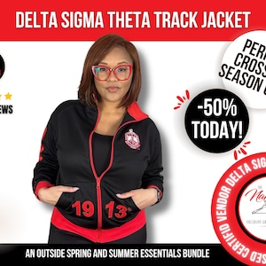 May include: Black track jacket with red trim and the Greek letters Delta Sigma Theta embroidered on the chest. The jacket has a zipper closure and two pockets. The text "1913" is printed in red on the front of the jacket.