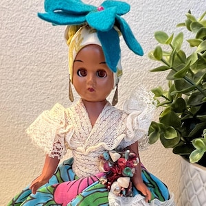 POUPÉE CHIQUITA DE L&#39;ÎLE VIERGE DES ANNÉES 1950, 20 cm H Poupée folklorique ethnique traditionnelle, yeux ambrés endormis, coquillages et paillettes embellis, support en plastique