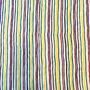 May include: A close-up view of a quilted fabric with vertical stripes in various colors. The stripes include red, yellow, green, blue, and black, set against a white background. The quilting pattern features diagonal stitching.