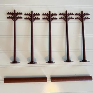 May include: Five brown plastic model utility poles with crossarms and small insulators, arranged in a row, accompanied by two separate brown cylindrical plastic rods positioned horizontally below the poles.