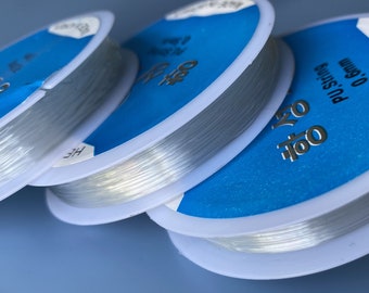 May include: Four spools of clear elastic string, each with a blue and white label. The label reads "0.8mm PU String".