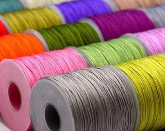 May include: A collection of spools of colorful waxed cotton cord, arranged in a row. The spools are made of plastic and have a clear window to see the cord. The cord is available in a variety of colors, including red, orange, yellow, green, blue, purple, pink, and brown.