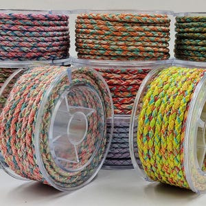 May include: A collection of colorful braided cord spools. The spools are filled with various colors, including pink, blue, orange, green, and yellow. The cord is tightly woven and appears to be made of a durable material. The spools are clear plastic.