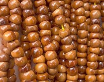 May include: A close-up of a strand of brown wooden beads. The beads are round and have a smooth, polished finish.