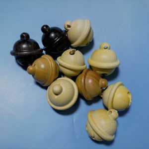 K&ouml;nnte beinhalten: Eine Gruppe von Holzgl&ouml;ckchen in verschiedenen Braunt&ouml;nen und Beige. Die Gl&ouml;ckchen liegen auf einer hellblauen Oberfl&auml;che.