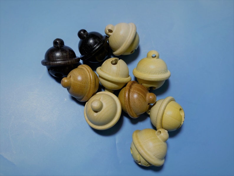 K&ouml;nnte beinhalten: Eine Gruppe von Holzgl&ouml;ckchen in verschiedenen Braunt&ouml;nen und Beige. Die Gl&ouml;ckchen liegen auf einer hellblauen Oberfl&auml;che.