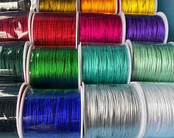 May include: A collection of spools of colorful waxed cord, each wound around a clear plastic spool. The colors include black, red, pink, purple, green, teal, silver, and white.