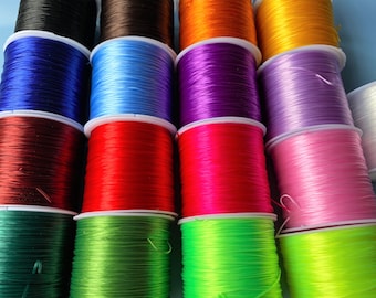 May include: Assortment of colorful elastic string spools in various colors, including black, brown, blue, purple, orange, yellow, red, pink, green, and neon green.
