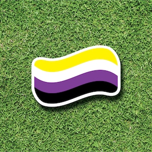 Può includere: Una bandiera arcobaleno gialla, bianca, viola e nera con un design ondulato. La bandiera è su uno sfondo di erba verde.