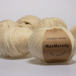 Könnte beinhalten: Fünf Knäuel cremefarbenes, dickes Wollgarn. Das Garn ist mit "MaxMelody Knit Studio" und "Chunky Wool 10-13mm" gekennzeichnet.