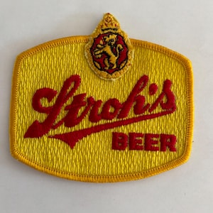 May include: A yellow embroidered patch with the words "Strohs's Beer" in red lettering. A small yellow and red lion emblem is in the top center of the patch.
