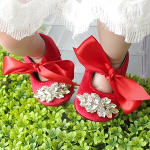 Peut inclure: Chaussures de b&eacute;b&eacute; en velours rouge avec un grand embellissement en strass et un n&oelig;ud en satin rouge.