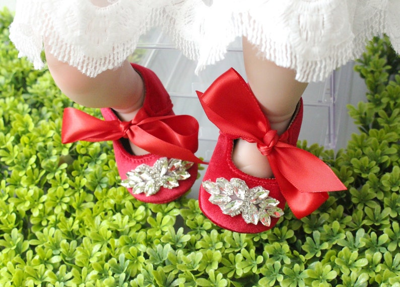 Peut inclure: Chaussures de b&eacute;b&eacute; en velours rouge avec un grand embellissement en strass et un n&oelig;ud en satin rouge.