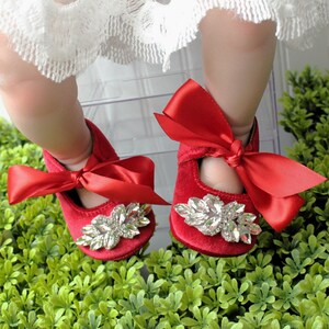 Peut inclure: Chaussures de b&eacute;b&eacute; en velours rouge avec un grand embellissement en strass et un n&oelig;ud en satin rouge.