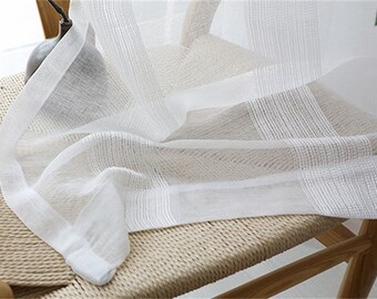 May include: White sheer curtains with a subtle striped pattern. The curtains are draped over a wooden chair with a woven seat.