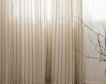 May include: A pair of sheer, white linen curtains with thin, black stripes. The curtains are hanging in a window and are letting in natural light.