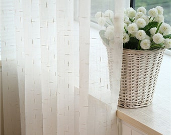 May include: White sheer curtains with a subtle grid pattern. The curtains are hung in a window with a wooden frame and a white wall. A wicker basket filled with white flowers sits on the windowsill.
