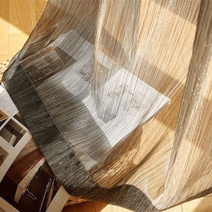 May include: A sheer curtain with a brown and white striped pattern and a black border. The curtain is made of a lightweight fabric and has a subtle shimmer.