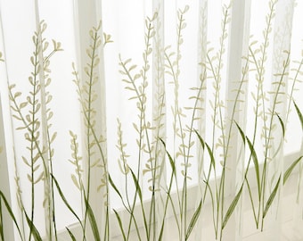 May include: Sheer white curtain panels with an embroidered floral design. The design features green stems and leaves with light green and beige flower heads. The curtains are semi-transparent, allowing light to filter through.
