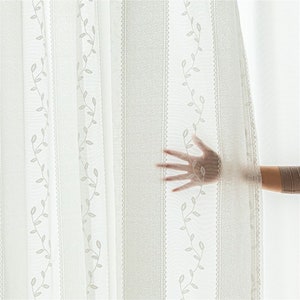 May include: White sheer curtains with a delicate leaf pattern. The curtains are semi-transparent, allowing light to filter through.