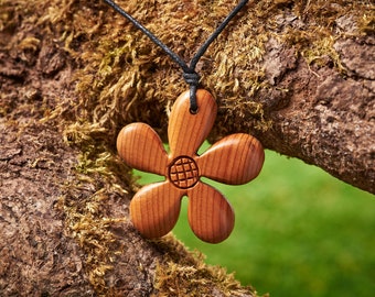 Ein Anhänger in Form einer Blume aus Irischer Eibe, befestigt an einem verstellbaren gewachsten Baumwollband.