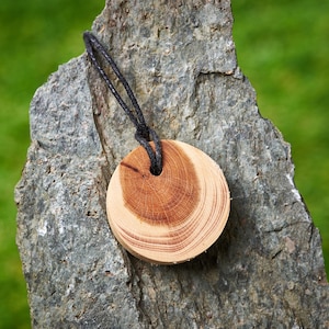Round wooden pendant made from English Yew hung on a adjustable Waxed Cotton Thong.