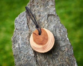 Round wooden pendant made from English Yew hung on a adjustable Waxed Cotton Thong.